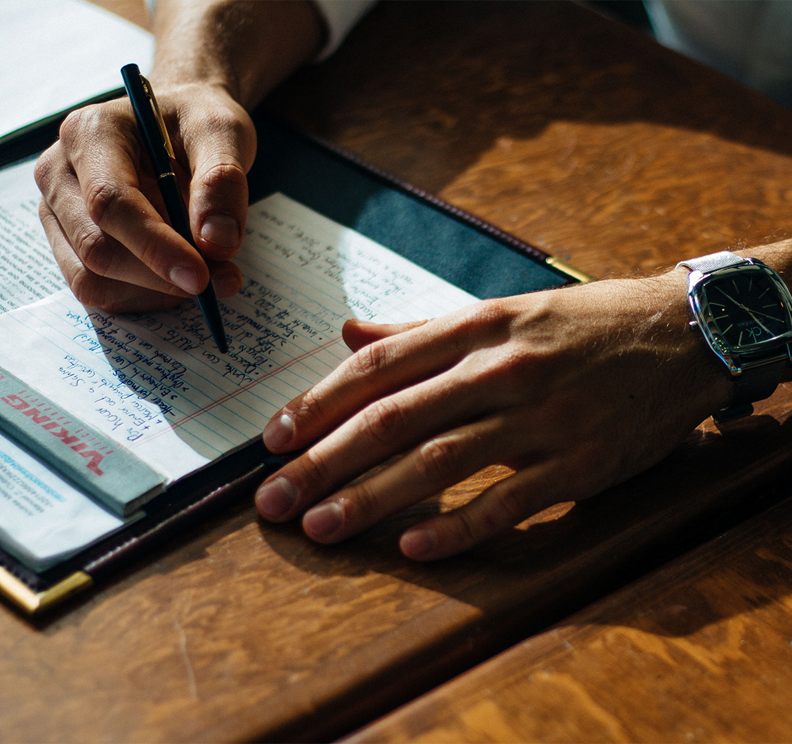 Image of person's hands holding pen and writing on a piece of paper